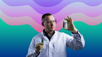 a scientist looking at material in a small jar