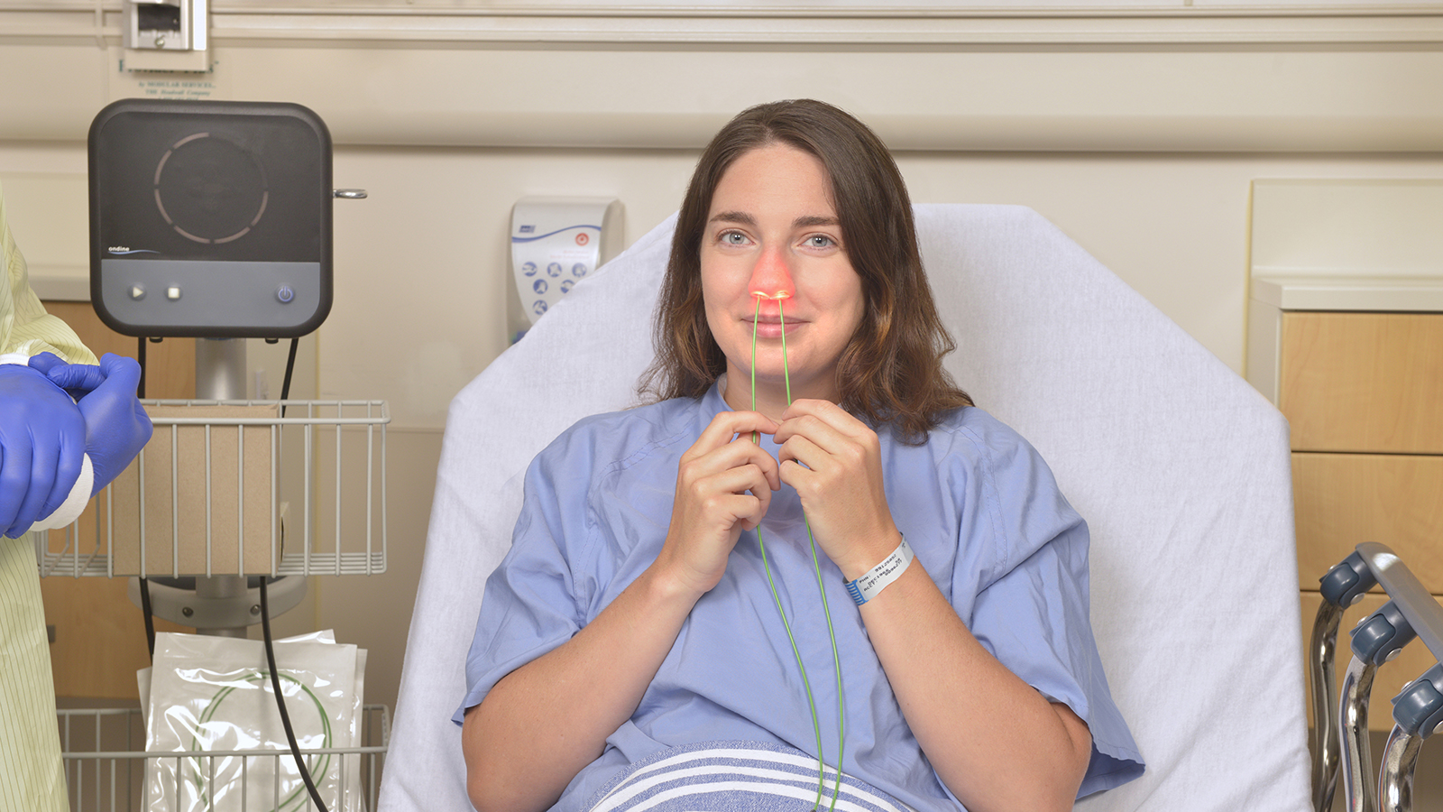 woman in hospital bed using nasal disinfecting device