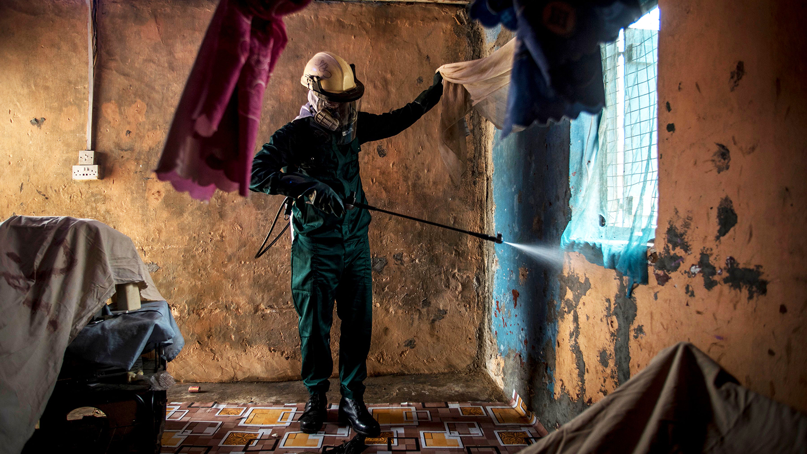 worker spraying pesticide inside a home