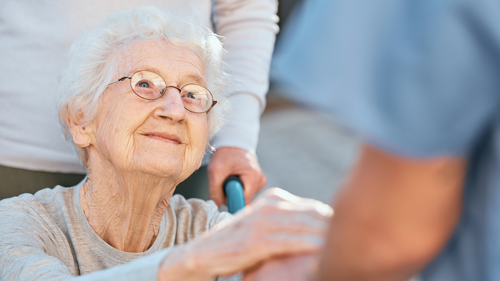 a seated older woman looking up toward a healthcare worker