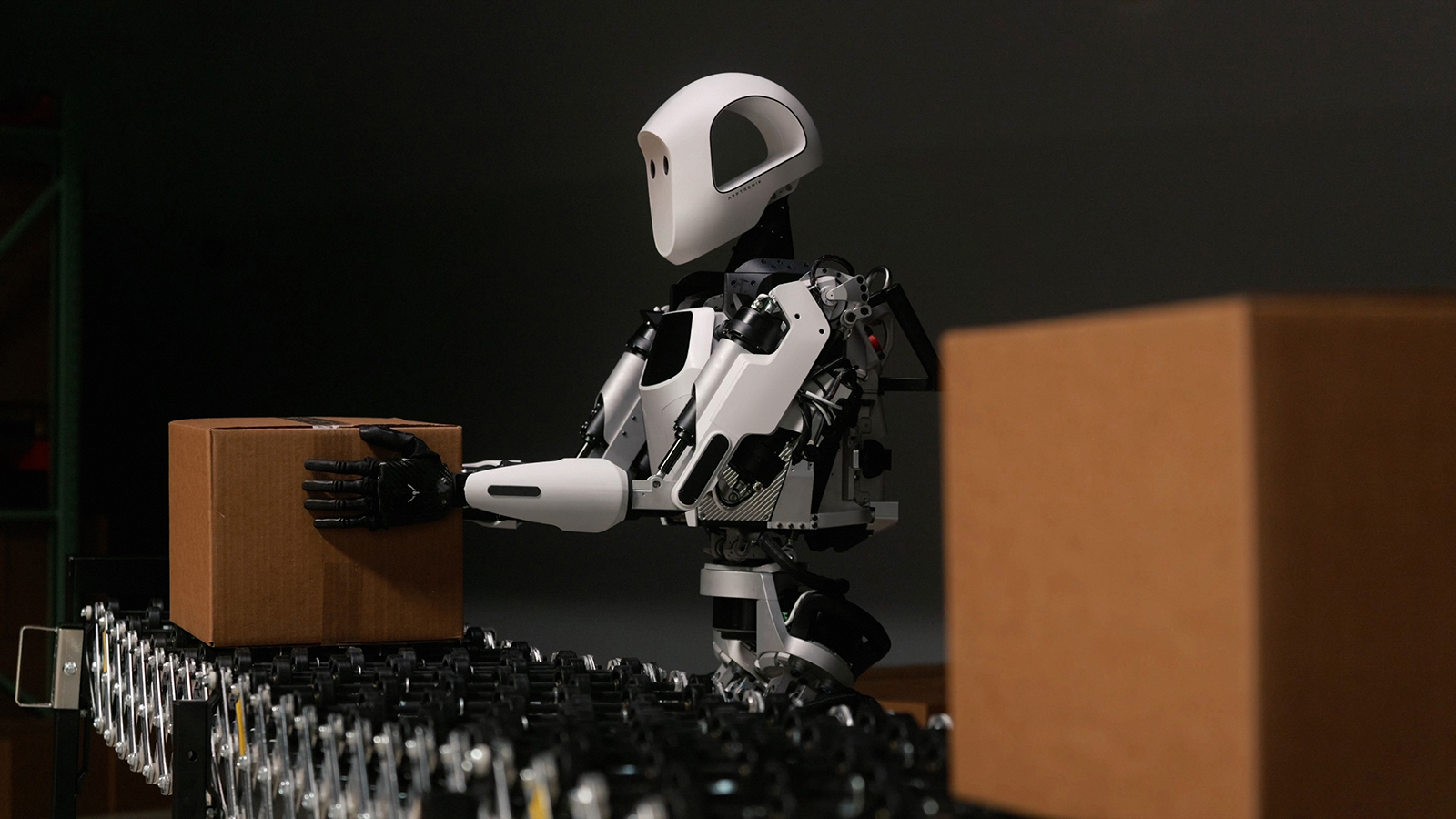 A humanoid robot is moving boxes in a warehouse.