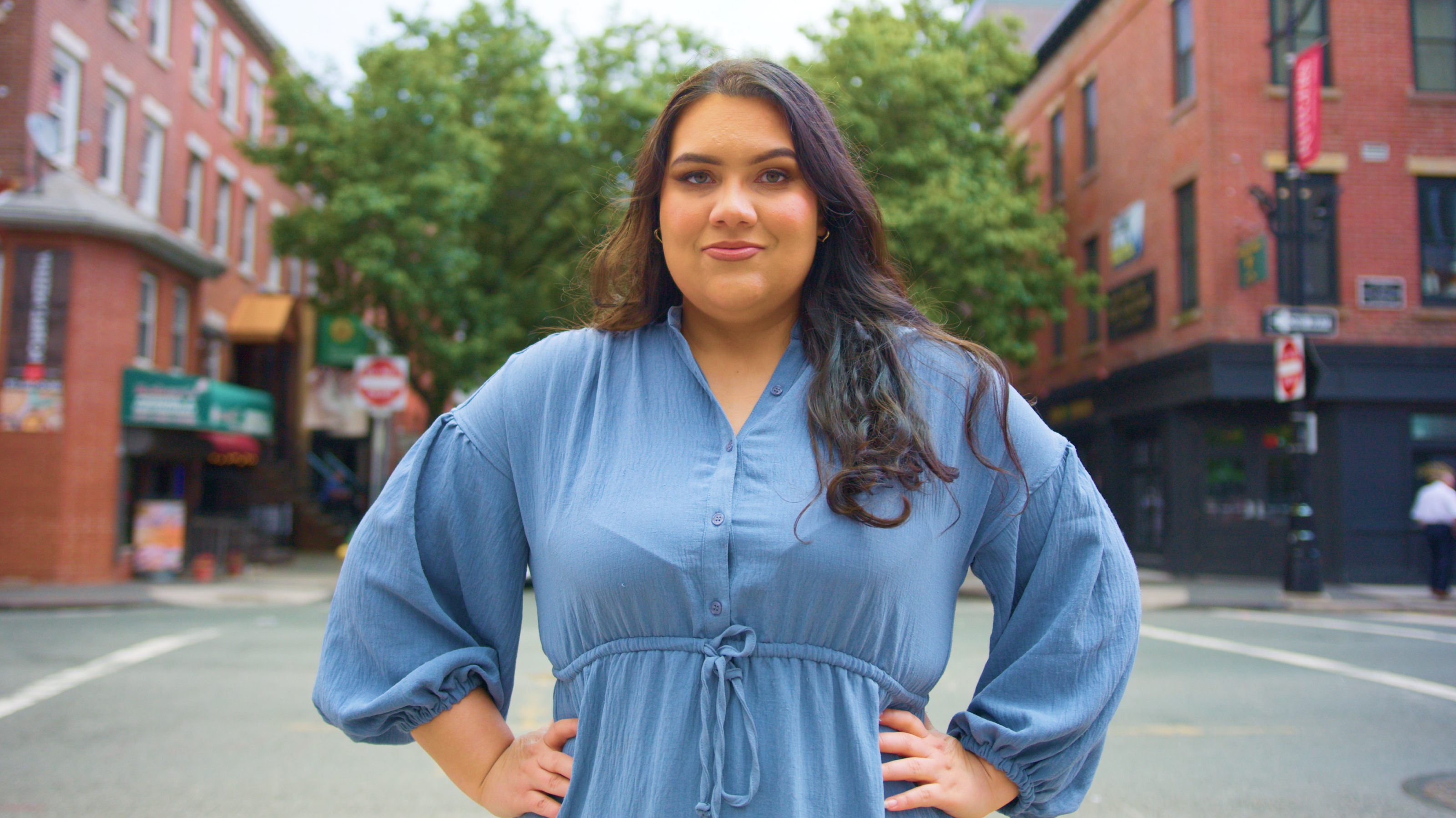 A woman in a blue dress standing on a street.