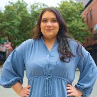 A woman in a blue dress standing on a street.