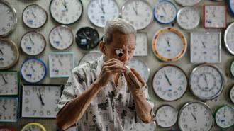 A man is standing in front of a wall of spacetime clocks.