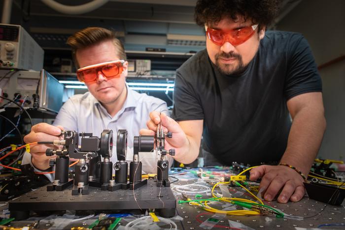 Two men in goggles are working on a machine.