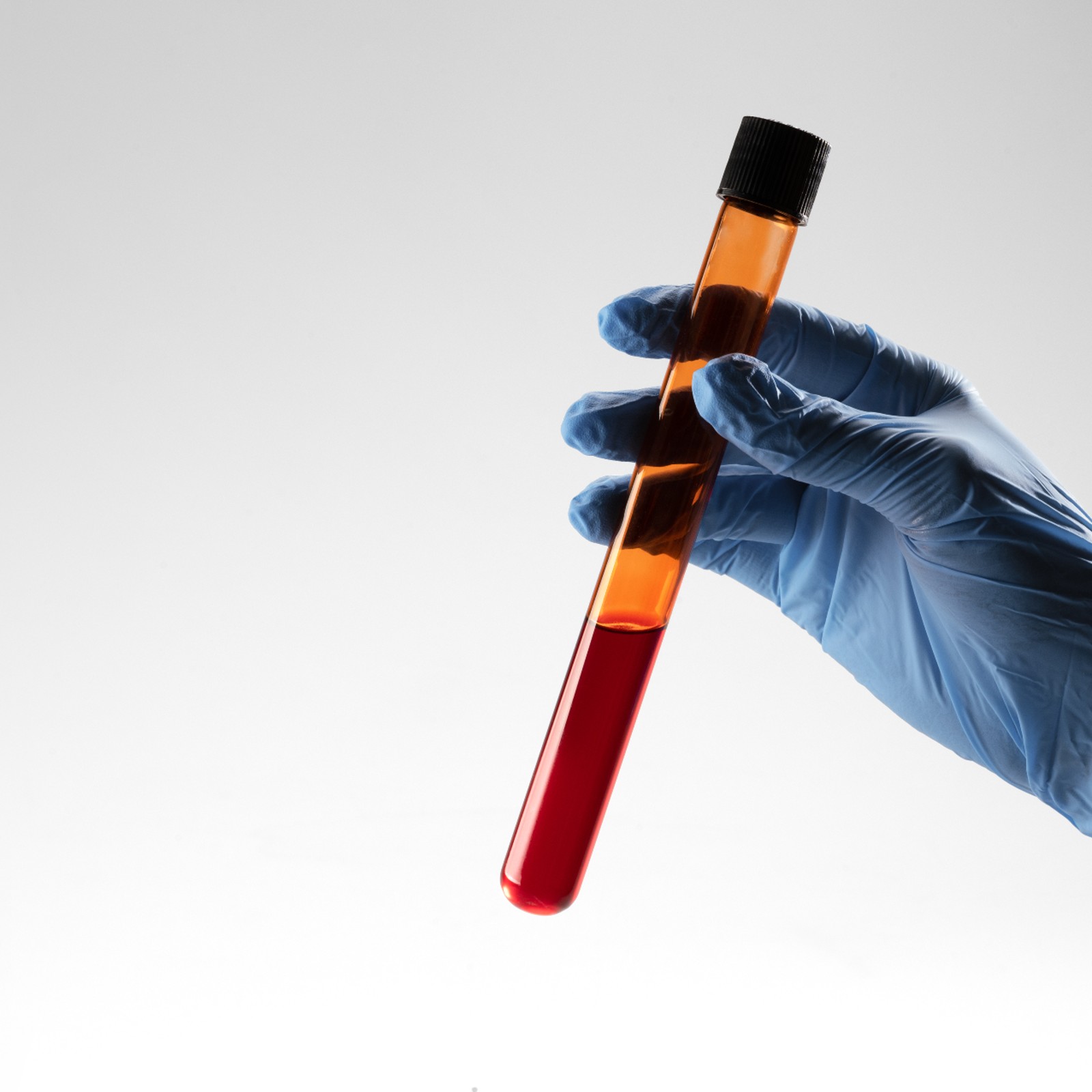 A person holding a test tube with oil in it.
