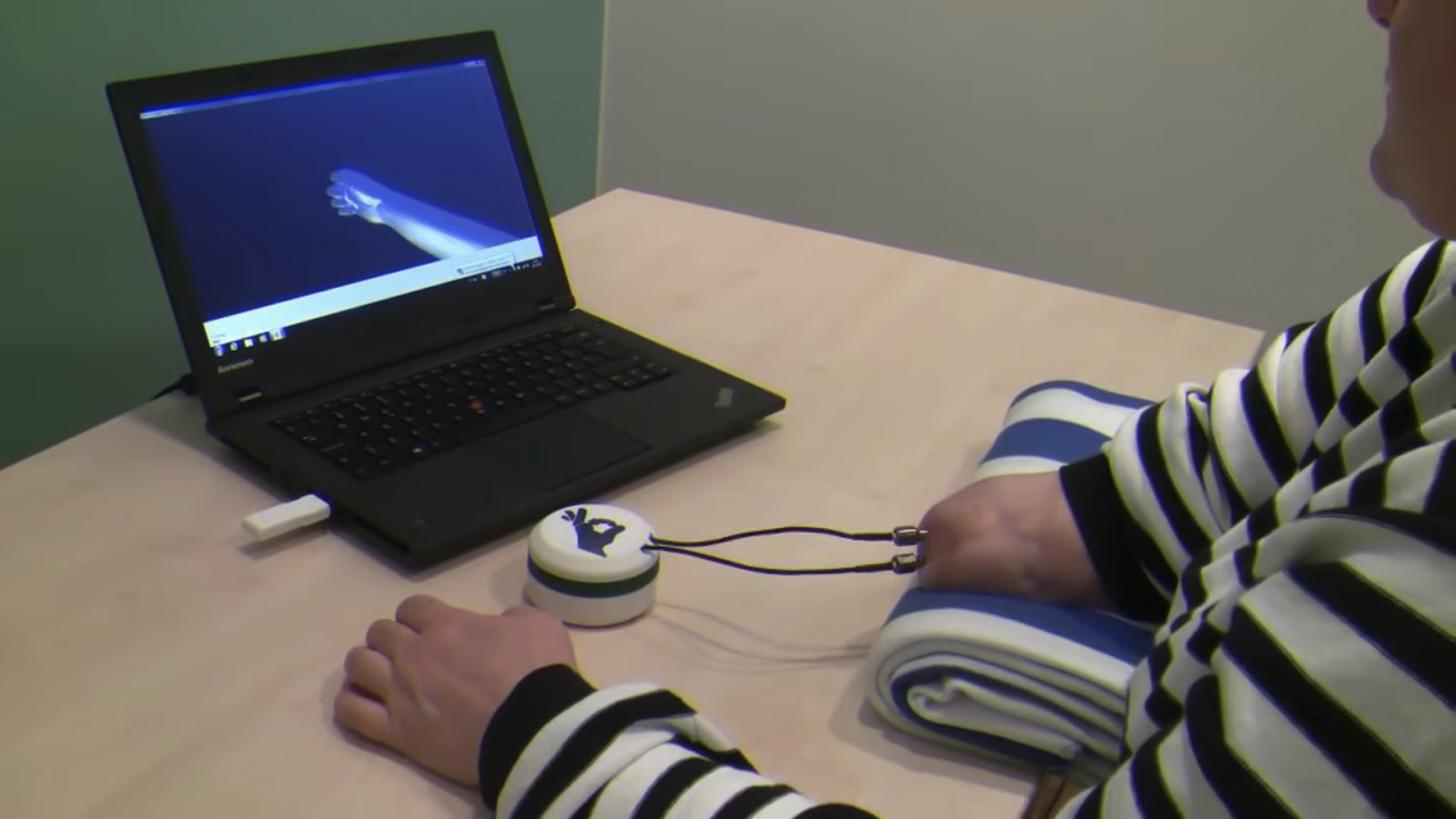 a woman sits at a desk using a computer to train bionic hand software