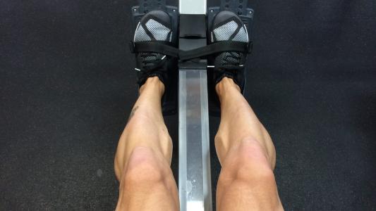 A person's legs on a rowing machine.