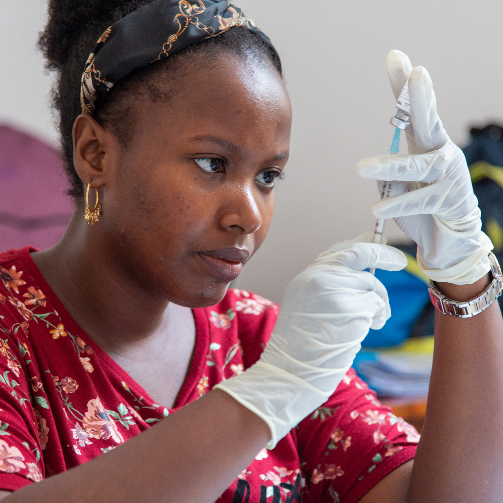 A woman preparing to administer a malaria vaccine with a syringe.