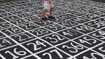 A boy is walking on a sidewalk with numbers painted on it.