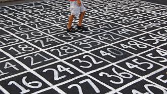 A boy is walking on a sidewalk with numbers painted on it.