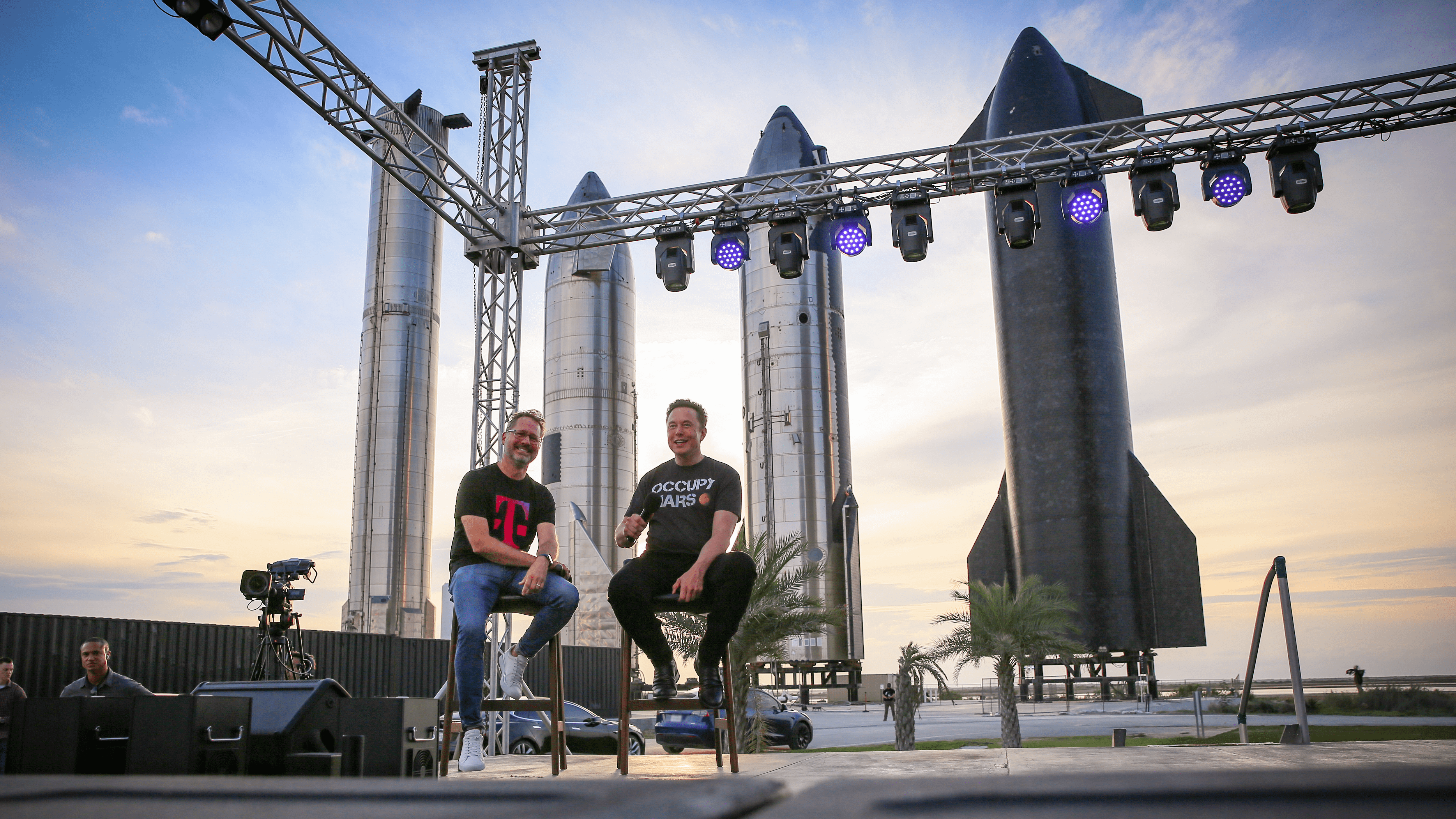 SpaceX CEO Elon Musk and T-Mobile CEO Mike Sievert on a stage with Starship rockets in the background