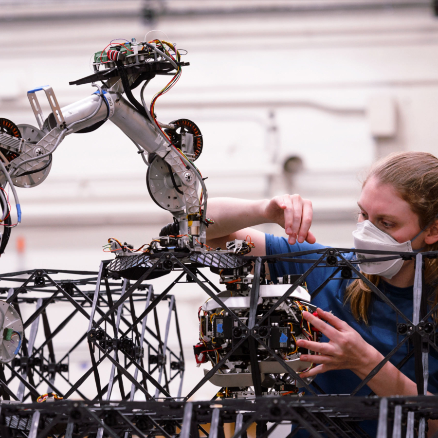 A woman is working with one of NASA's space robots as it builds a structure