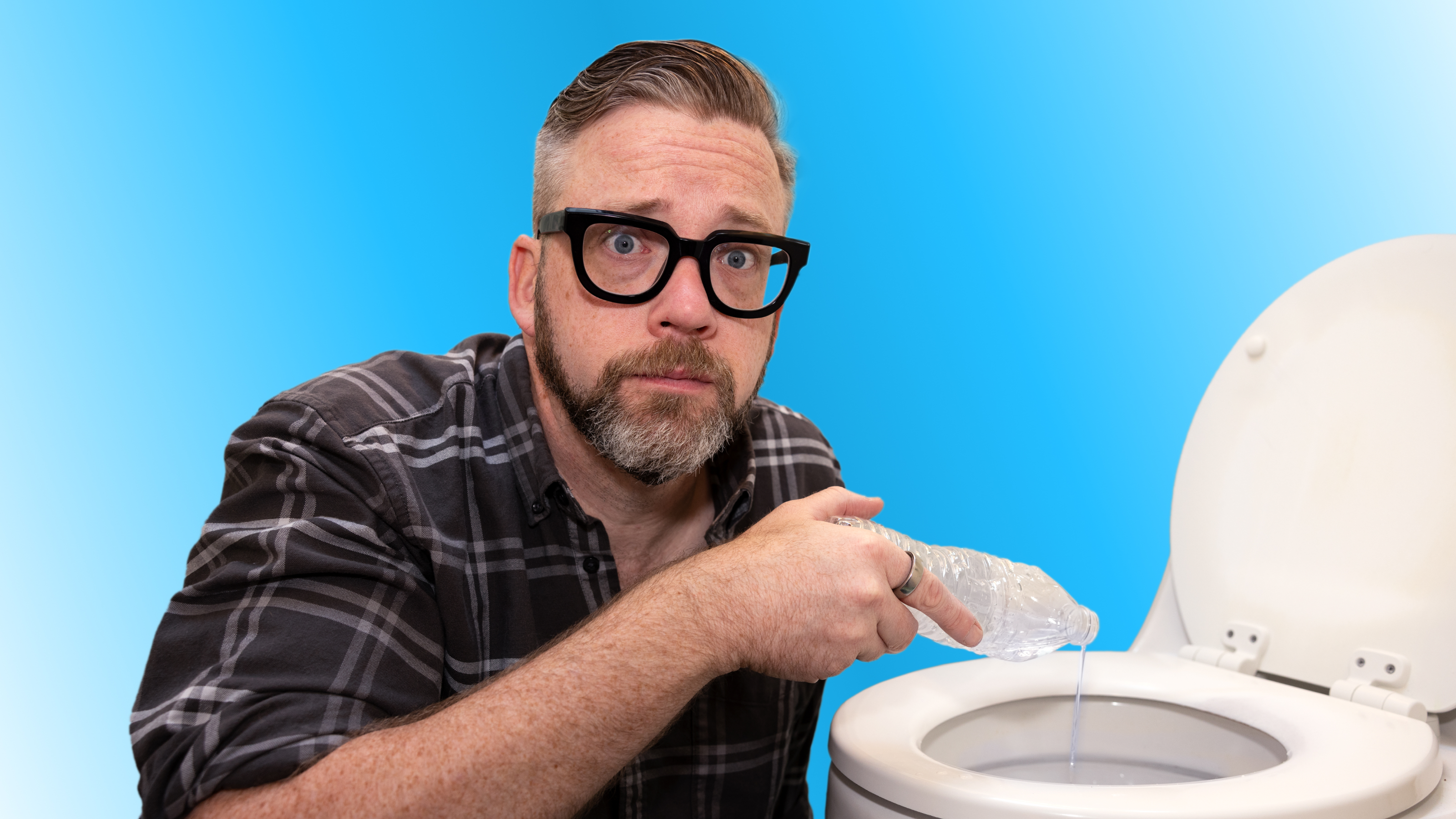 A man with glasses pours liquid from a plastic bag into a toilet against a blue background.